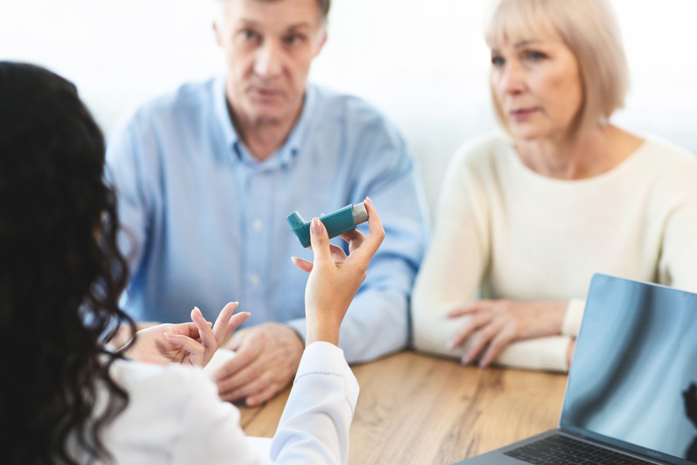 Doctor Holding Blue Asthma Inhaler For senior couple