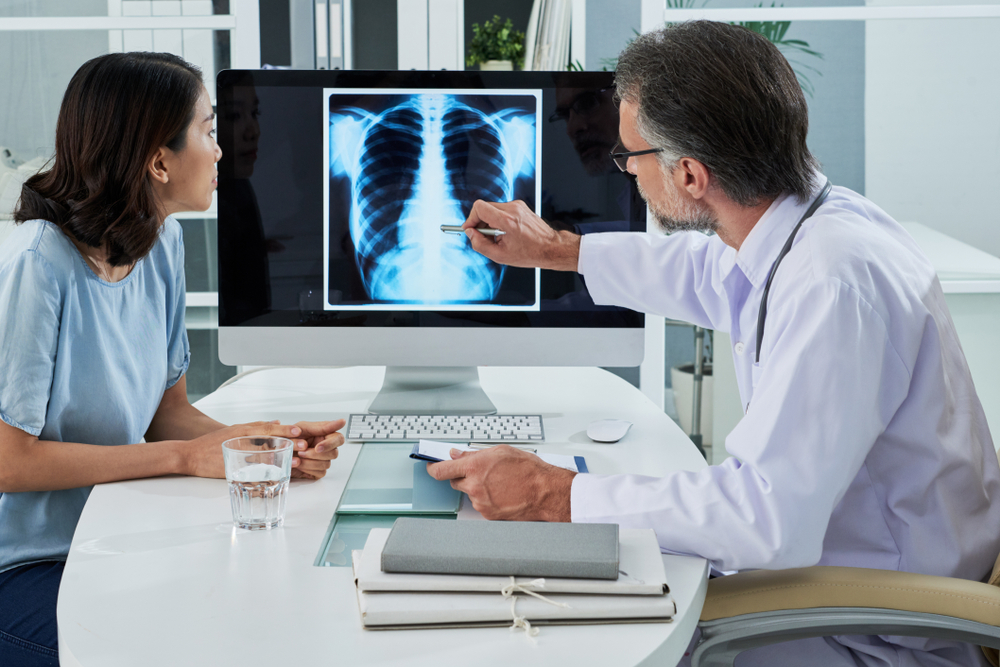 Doctor,Explaining,Lungs,X-ray,On,Computer,Screen,To,Young,Patient